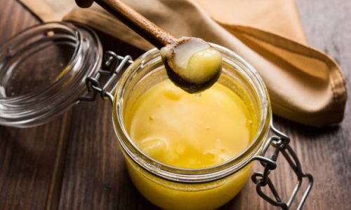 Desi Pure Ghee or clarified butter in glass or Copper container with spoon, selective focus